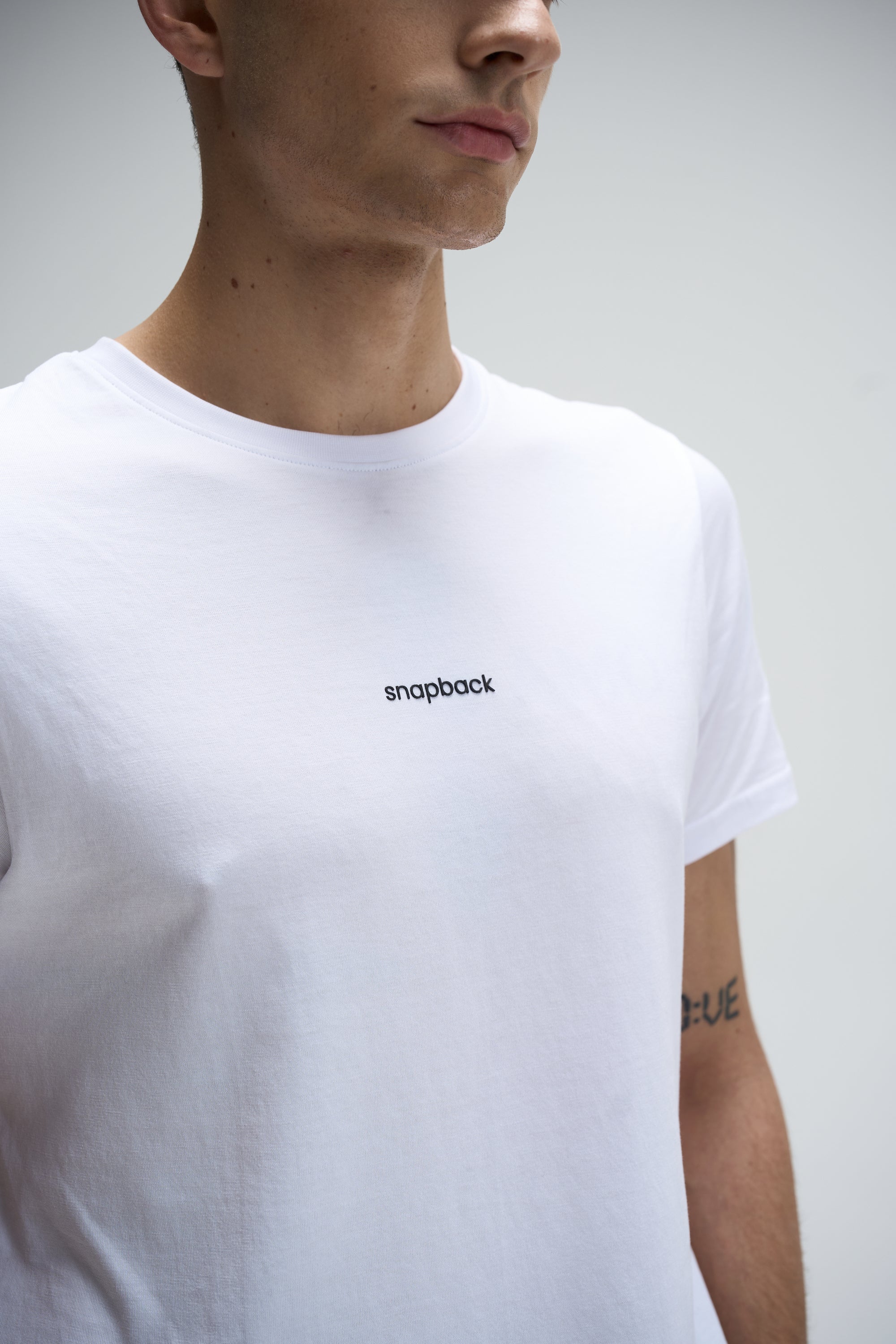 White crew neck Supima cotton t-shirt with small black "snapback" logo on chest, regular fit.