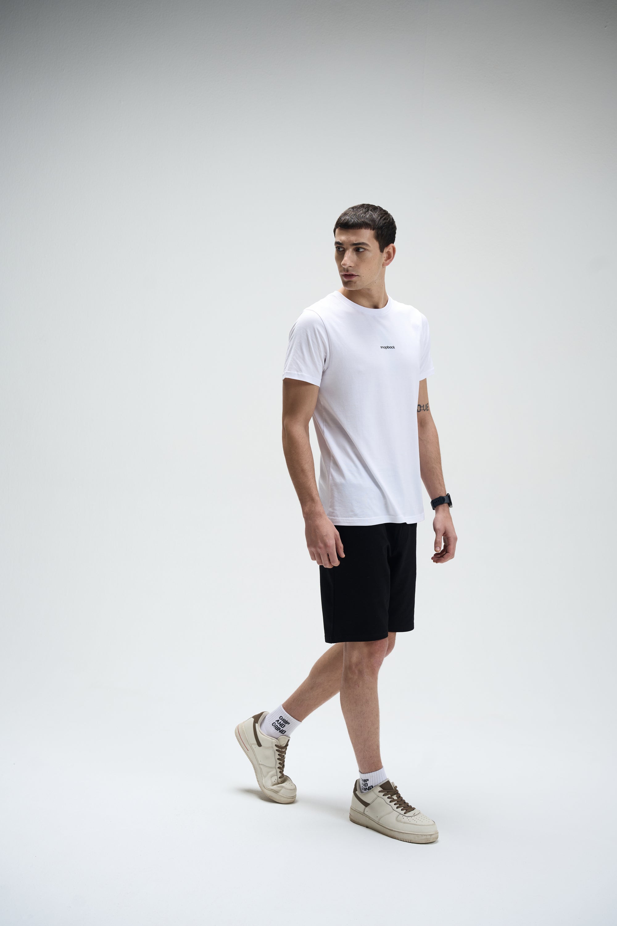 White Supima cotton crew neck T-shirt paired with black shorts and beige sneakers on male model.