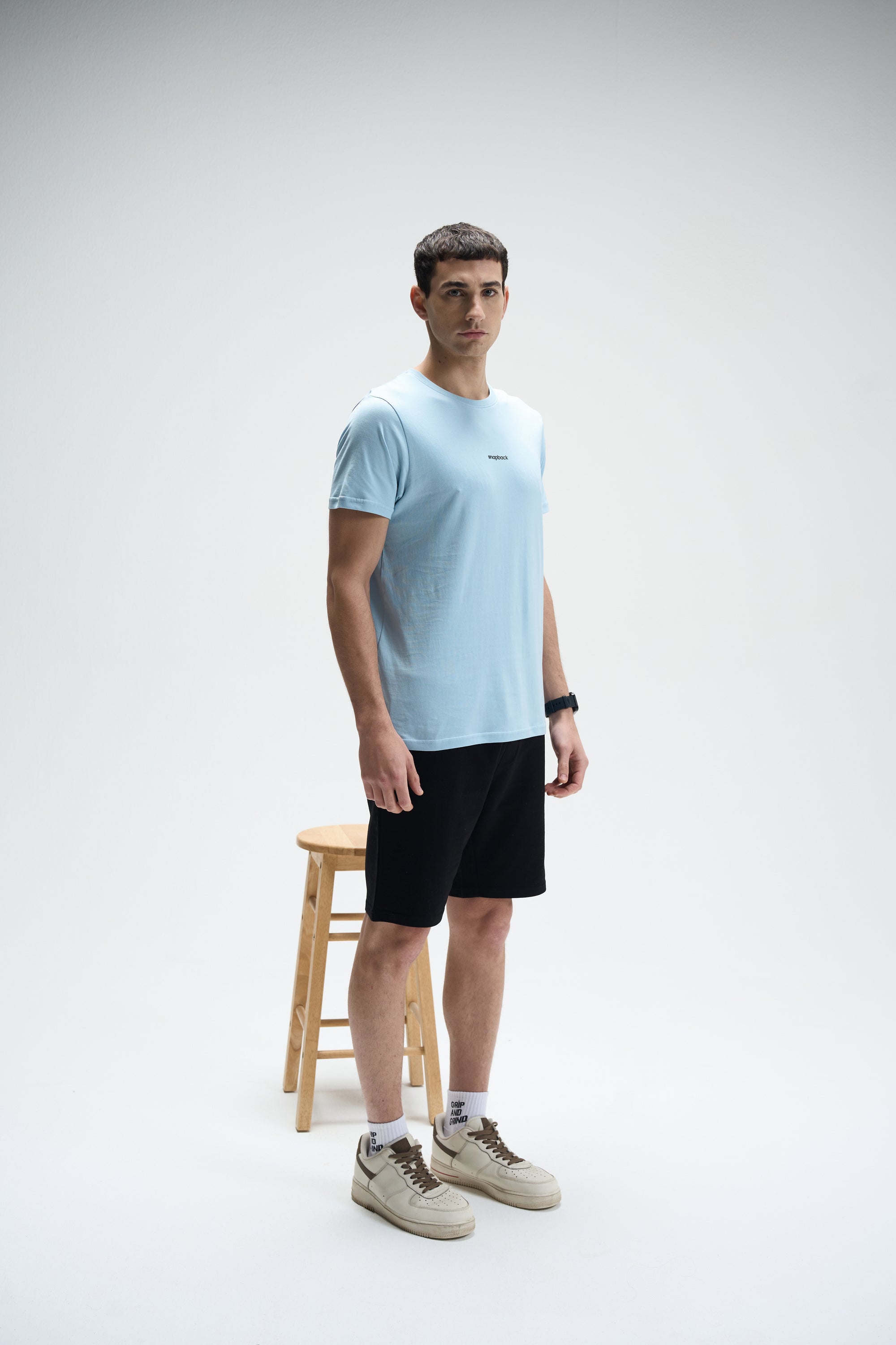 Light blue Supima cotton crew neck t-shirt paired with black shorts and beige sneakers on male model.