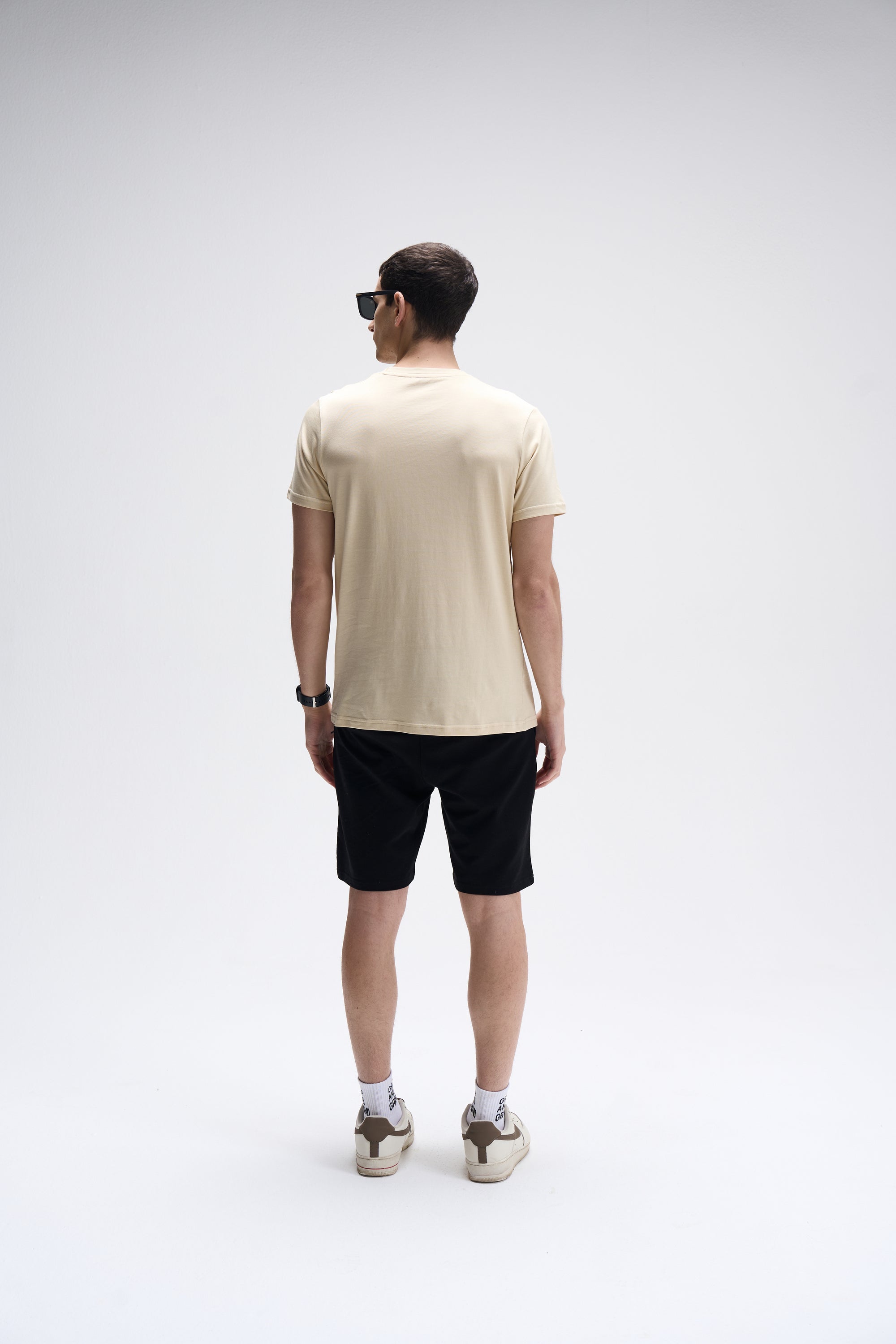 Men's soft sand crew neck T-shirt paired with black shorts, viewed from the back.